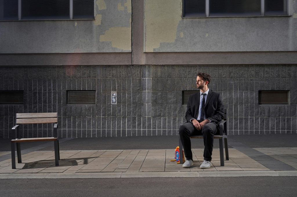 Ein Sprecher sitzt wartend auf einer Bank